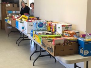 Several folding tables are piled with donated food and household items