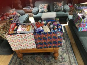 Big boxes of household items, festively wrapped, sit on a coffee table