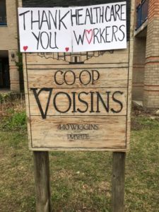 A wooden sign for Co-op Voisins, with a paper sign attached reading "Thank you healthcare workers!"