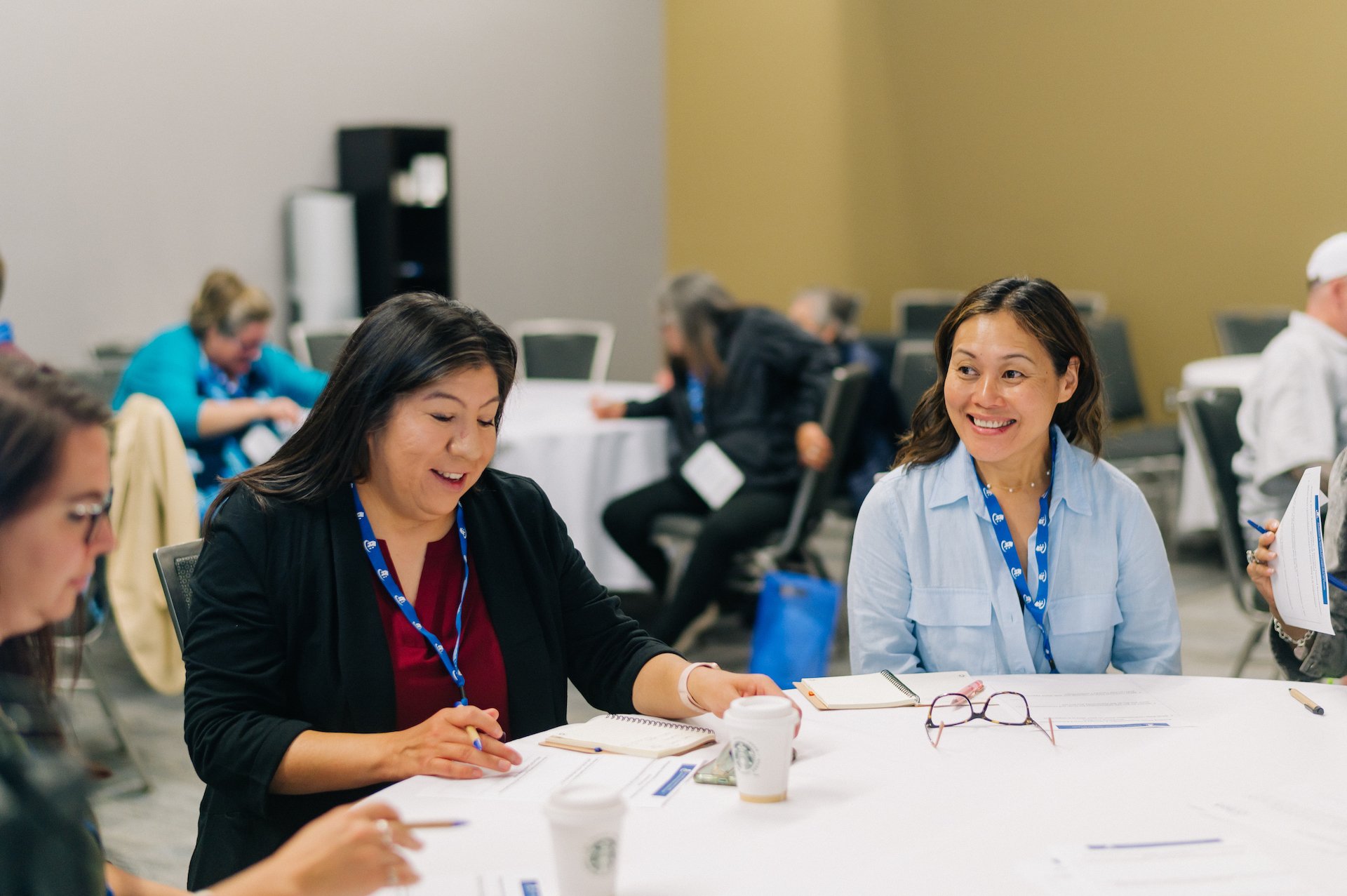 Four people sit around a table in a conference room, writing and talking about co-operative housing, with papers, notebooks, and coffee cups in front of them—reflecting the collaborative spirit of CHF Canada.